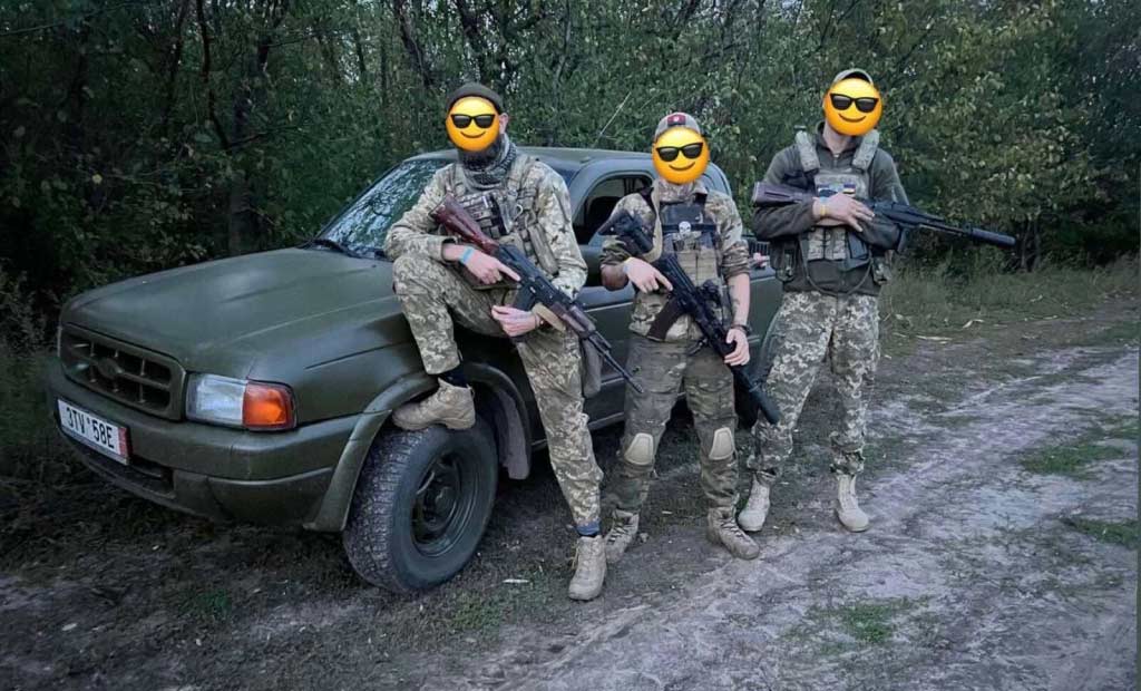 Three soldiers with covered faces near a car